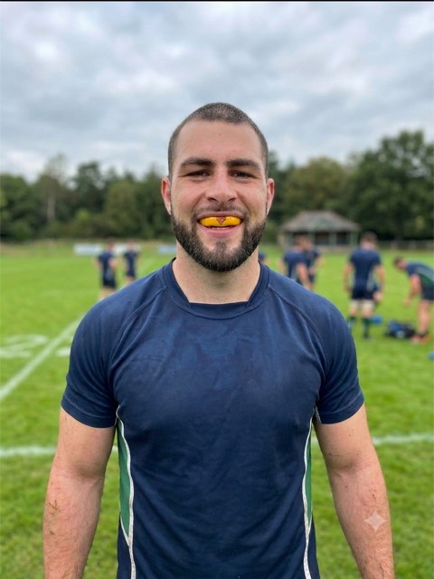 Adrian smiling with his custom gold Snugfit mouthguard